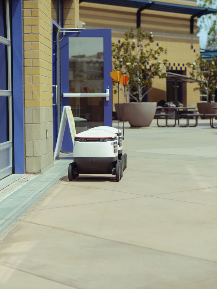 Autonomous delivery robot outside a building, showcasing modern technology.